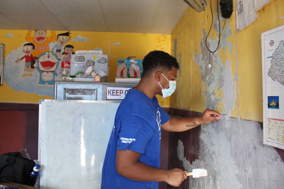 Shawn repairing a classroom wall during a school project